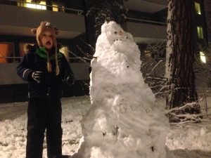 image shows small boy being terrified by an ugly snowman