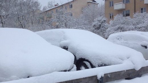 image shows cars completely covered in snow