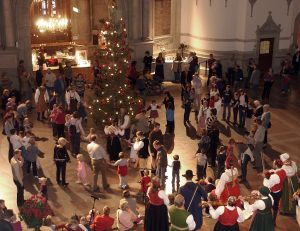 image shows people dancing around a Christmas tree