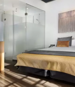 image shows hotel room with glass doors to toilet