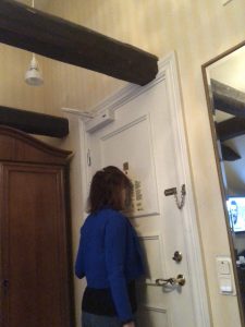 image shows a woman who is too short to reach the peephole in the door