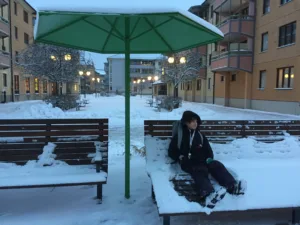 image shows person lounging under sun umbrella in the snow