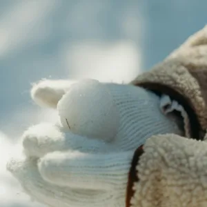 image shows person with gloves on handling snow